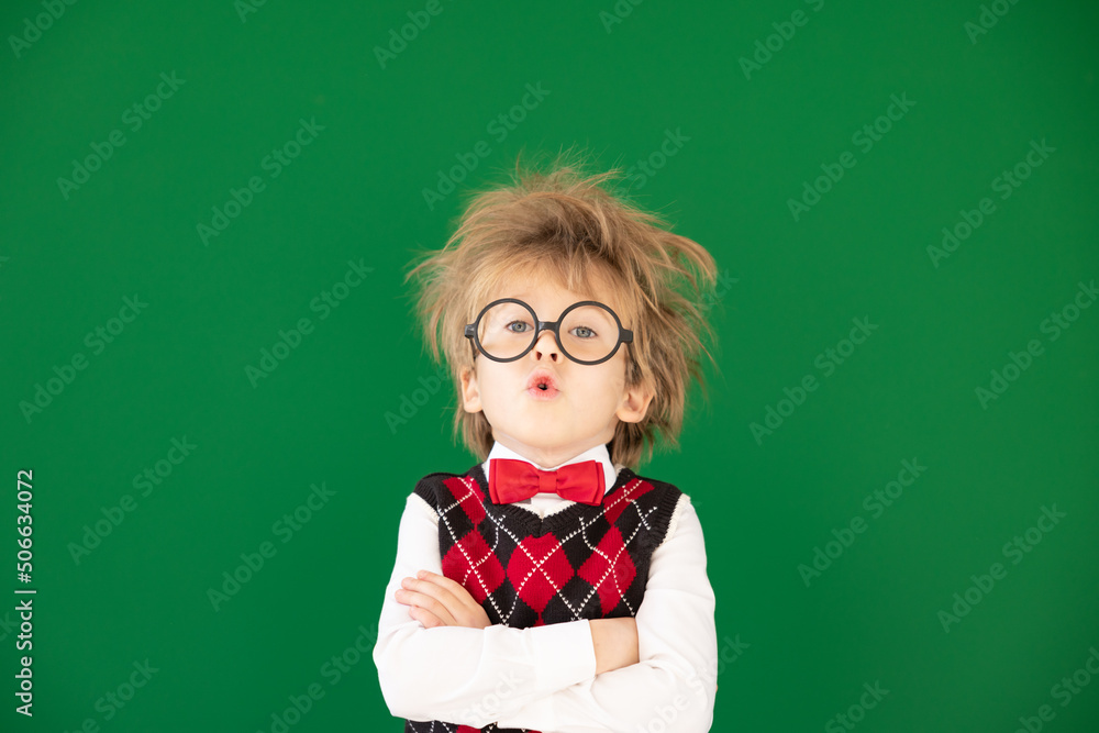 Happy child in class against green chalkboard