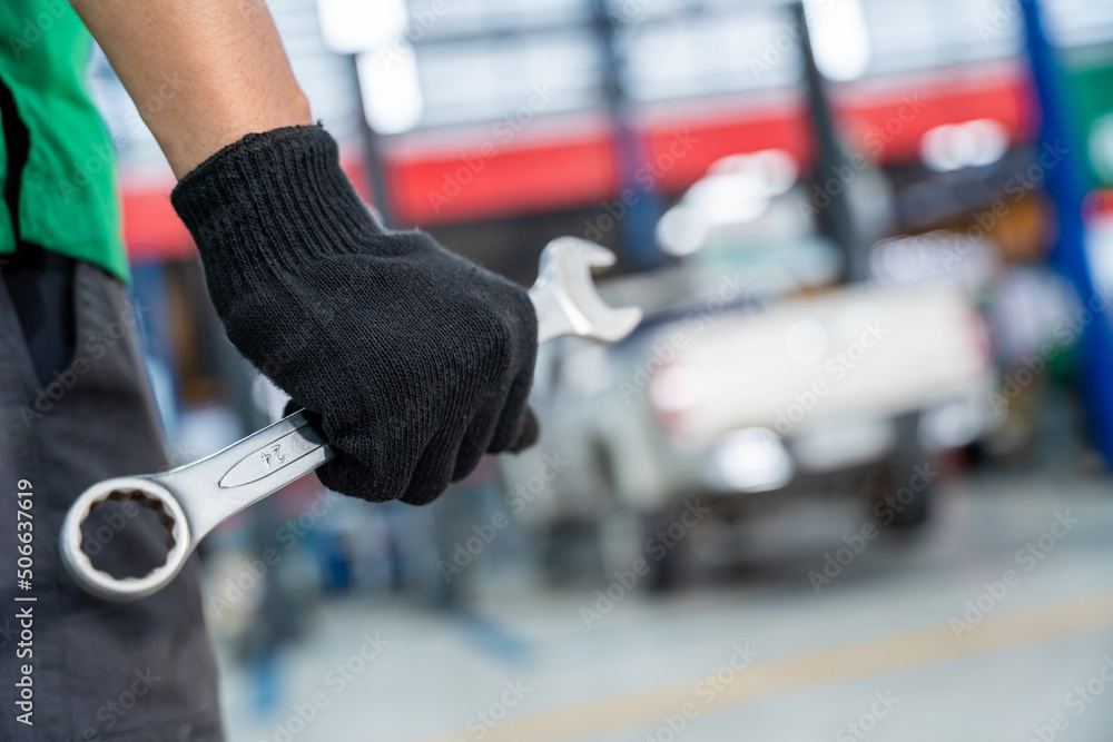 Auto Mechanic holding a wrench in Car repair service center.