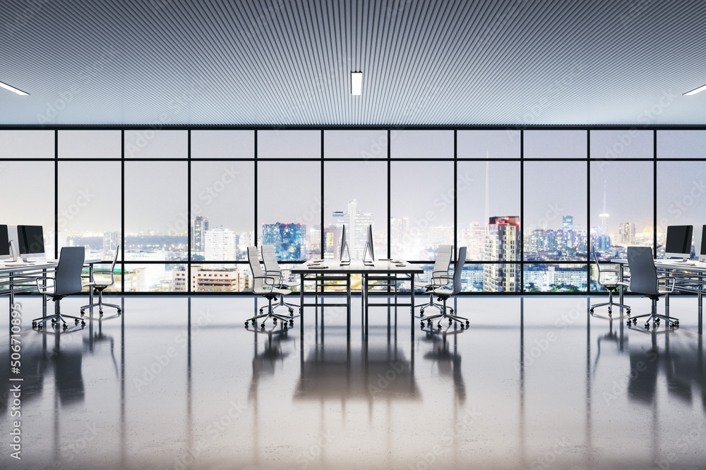 Side view on modern workplaces in spacious office with glossy floor and huge window with night city 