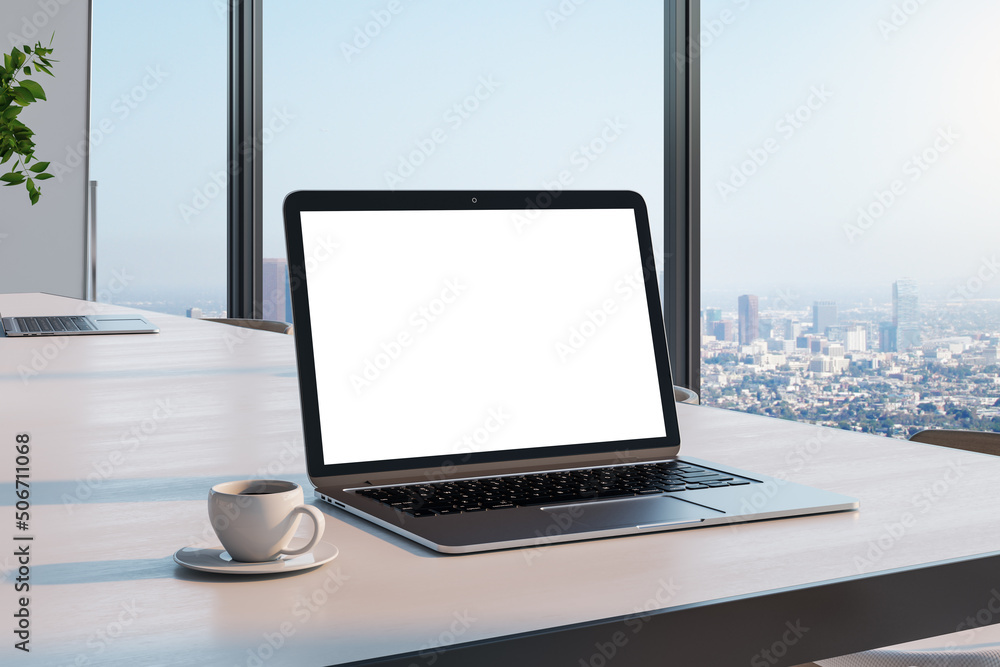 Blank white laptop screen with place for your text on wooden table with coffee mug in sunny room wit