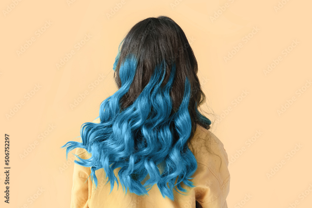 Beautiful young woman with unusual blue hair on color background