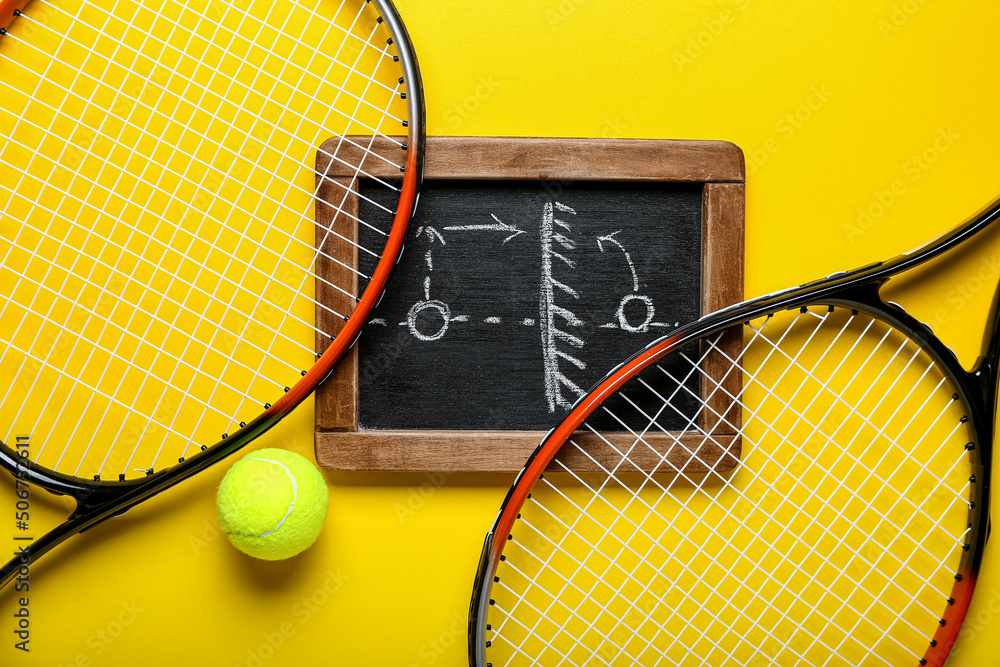 Chalkboard with drawn scheme of tennis game, ball and rackets on yellow background