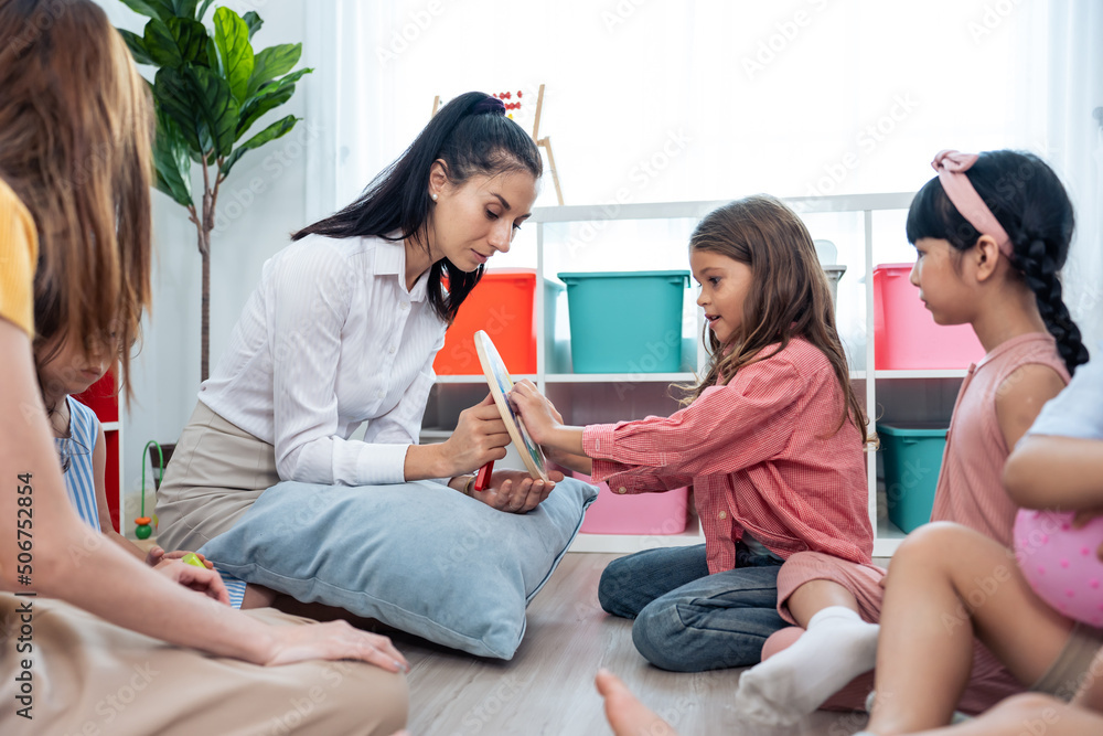 Caucasian beautiful woman teacher doing activity with kids at school. 