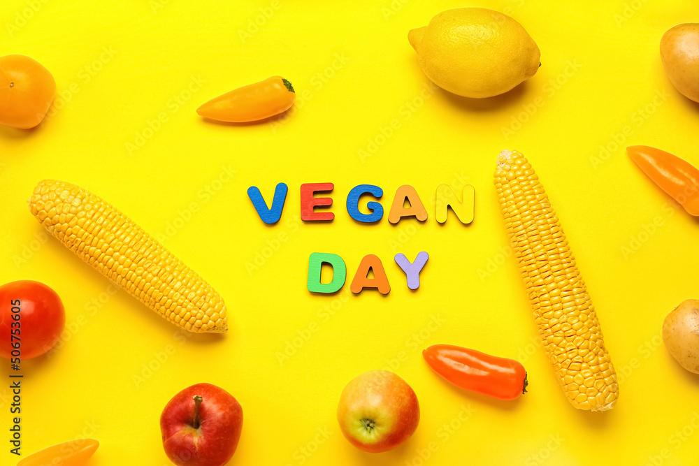 黄色背景上的新鲜蔬菜、水果和文字VEGAN DAY