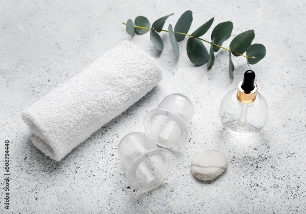 Composition with bottle of essential oil, clean towel and vacuum jars for anti-cellulite massage on 