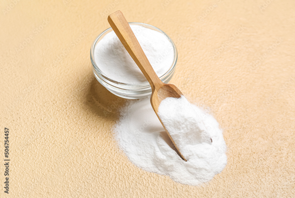 Bowl and spoon with baking soda on beige background