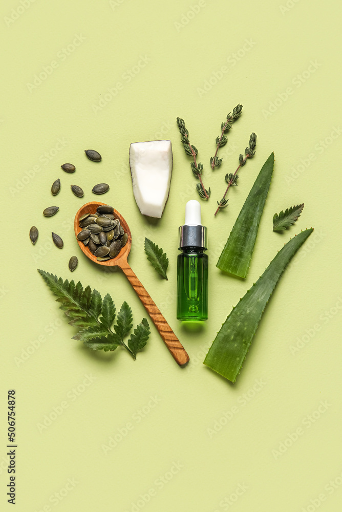 Bottle of natural serum, spoon with seeds, plant leaves, coconut and thyme on green background