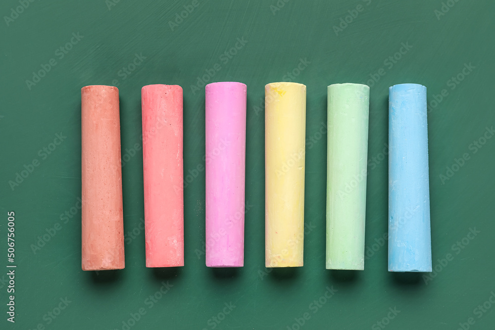 Colorful chalks on green blackboard