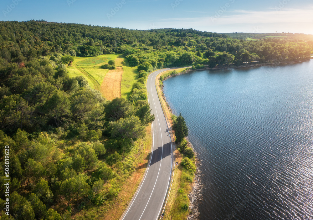 Aerial view of road near blue sea, forest at sunset in summer. Travel in Croatia. Top view of beauti