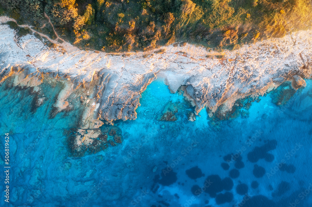 Aerial view of blue sea, rocks in clear water, beach, green trees at sunset in summer. Adriatic sea,