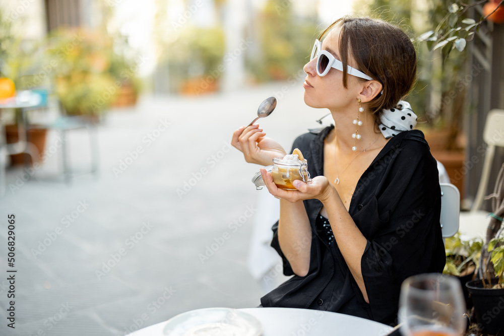 Woman eating tiramisu dessert at the restaurant outdoors. Concept of italian cuisine