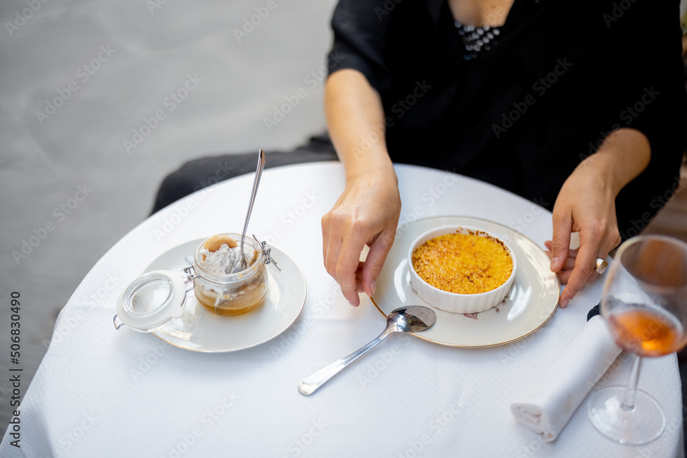 Woman eating dessert with creme brulee at the restaurant outdoors. Concept of italian cuisine