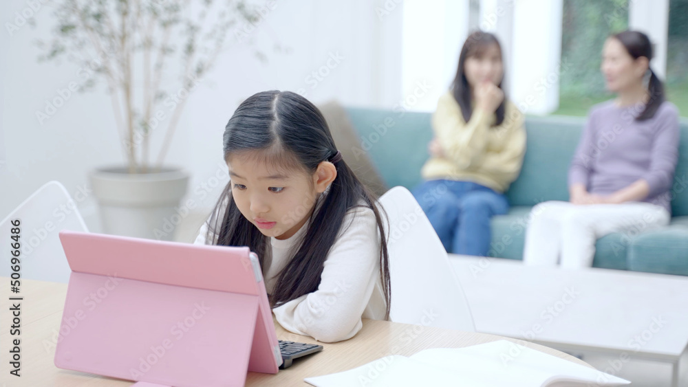 タブレットを使って学習をする女の子と見守る家族