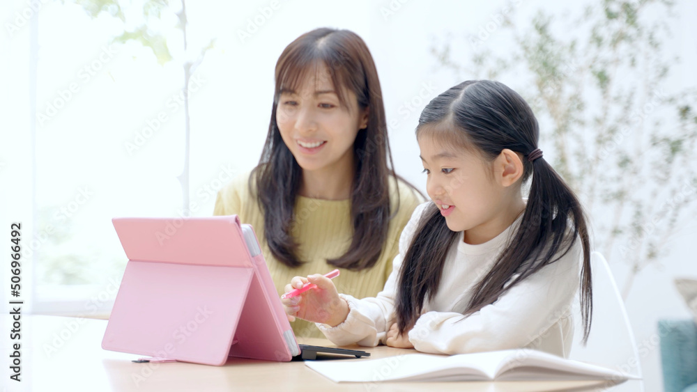 タブレットを使って学習をする女の子と見守るお母さん