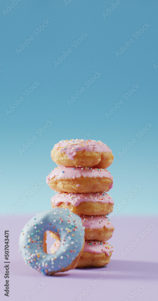 Vertical image of stack of donuts with pink and blue frosting on pink and blue background