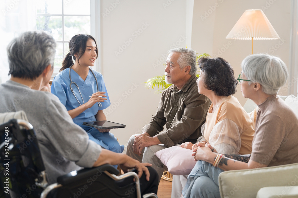 一群亚洲老年人在疗养院围成一圈，在集体活动中听护士讲话