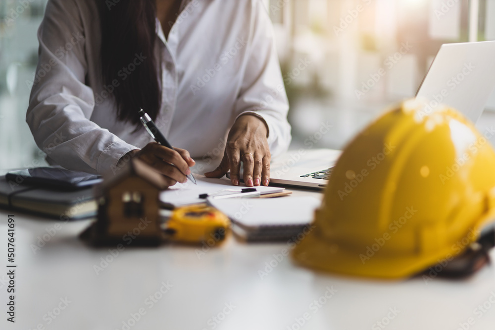 Female architect designer works on laptop and writes construction projects in office.