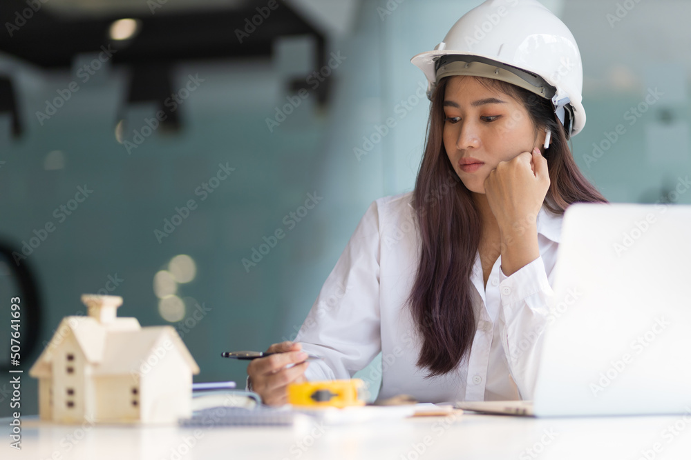 办公室里的女建筑设计师正在用笔记本电脑为房子建模并写房子