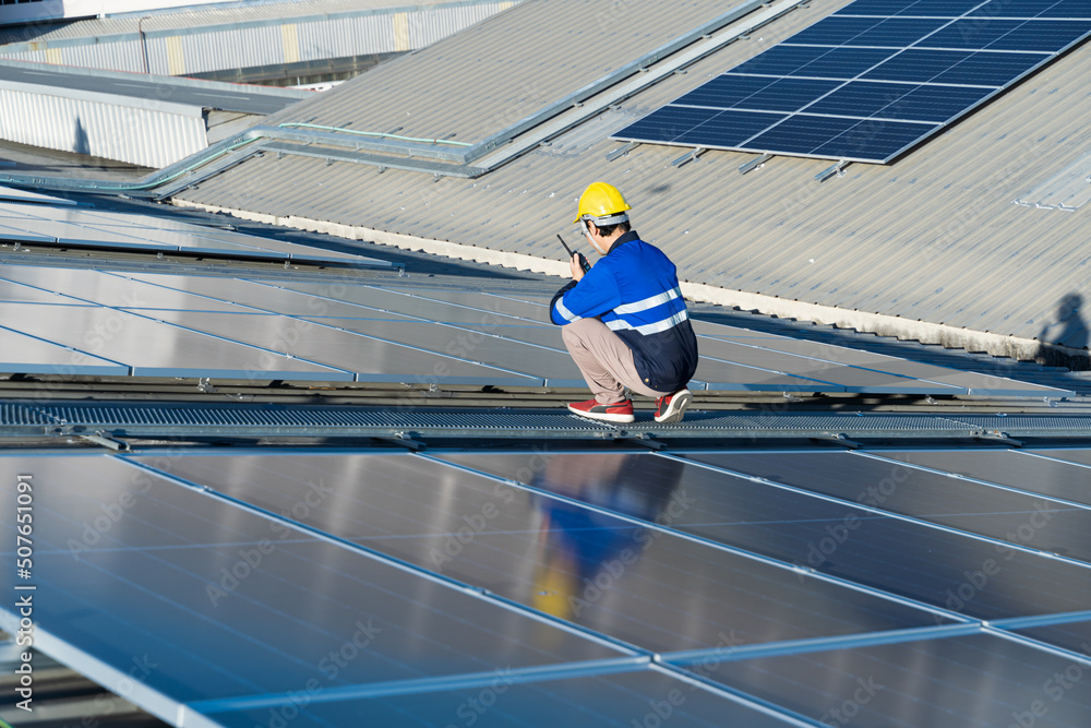 Asian technician installing inspection or repair solar cell panels on background field of photovolta