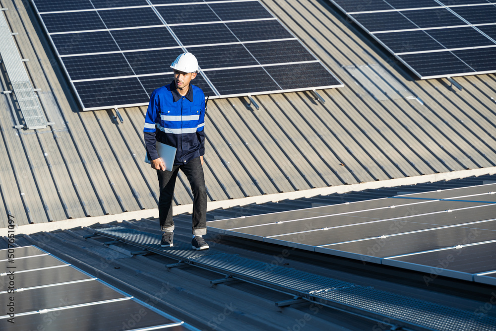 Portrait of Asian engineer on background field of photovoltaic solar panels solar cells on roof top 