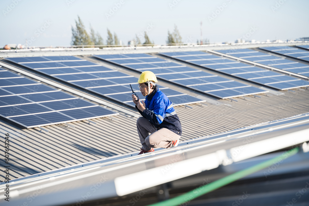 亚洲技术人员在光伏背景场安装检查或维修太阳能电池板