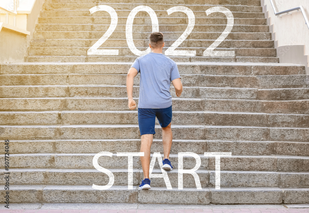 Sporty young man running up the stairs outdoors. Concept of 2022 goals