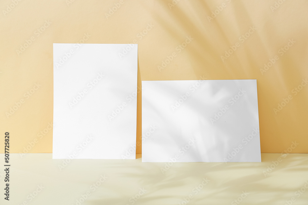 Two blank sheets of paper with shadow on color background