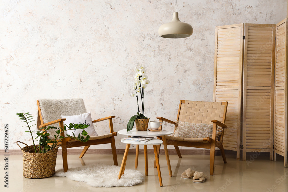 Interior of room with armchairs and table near light wall