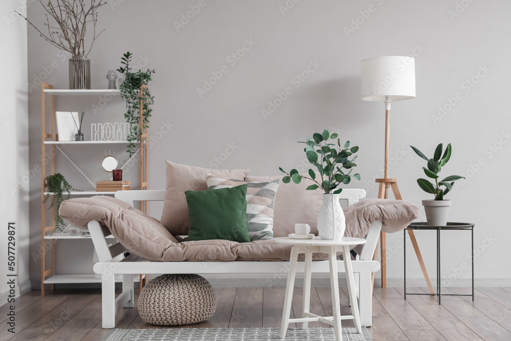 Interior of light living room with couch and eucalyptus in vase