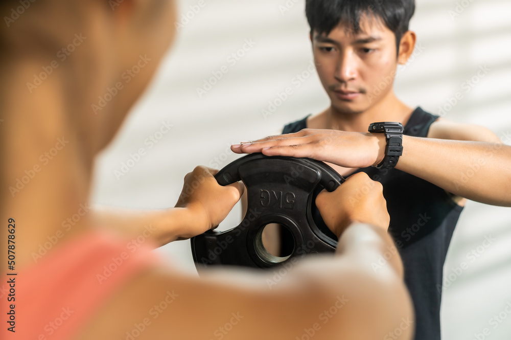 Fitness trainer assisting customer for working out during exercise