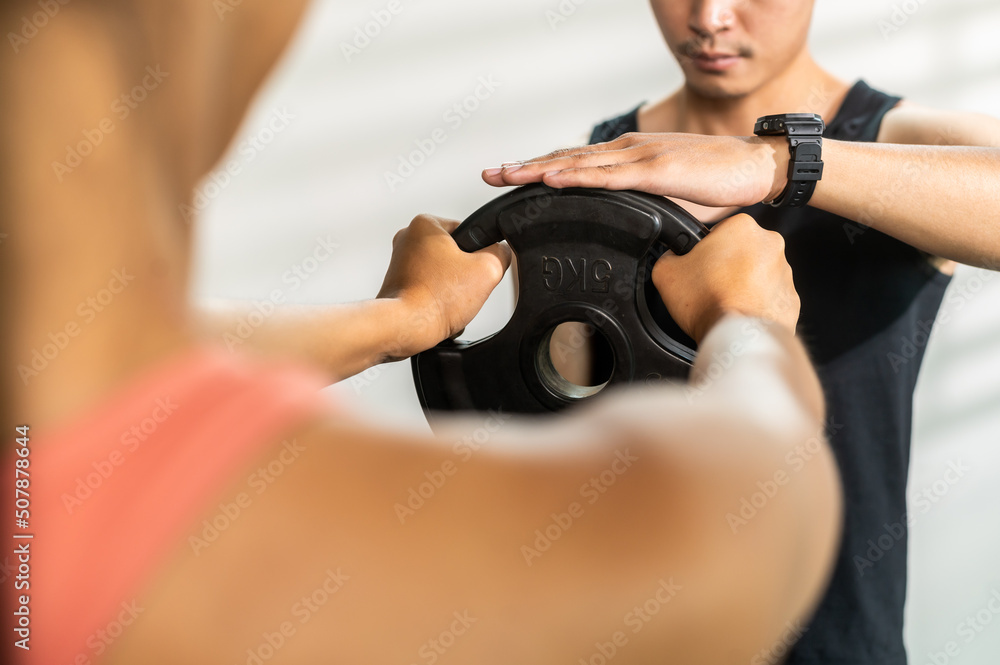 Fitness trainer assisting customer for working out during exercise