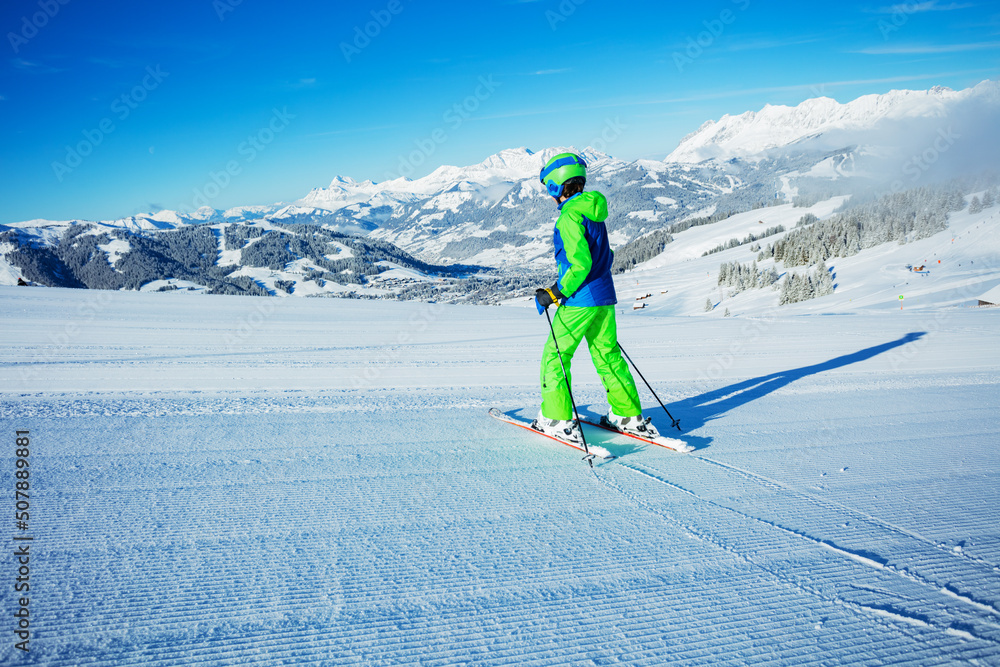 Back view of the preteen boy alpine ski go down fresh skiing