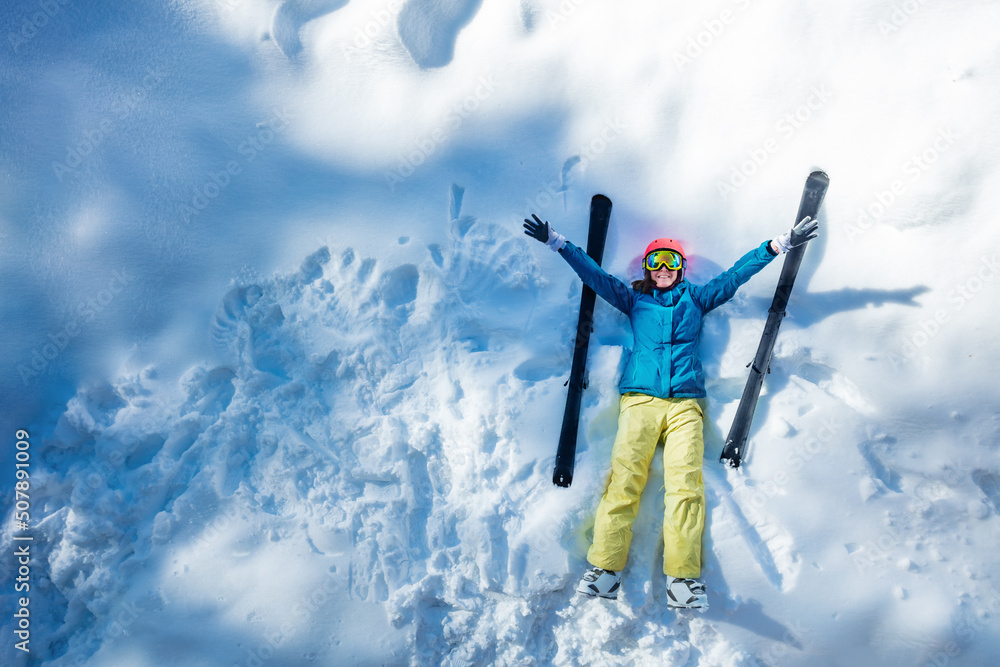 滑雪女人躺在雪地里，快乐地挥手