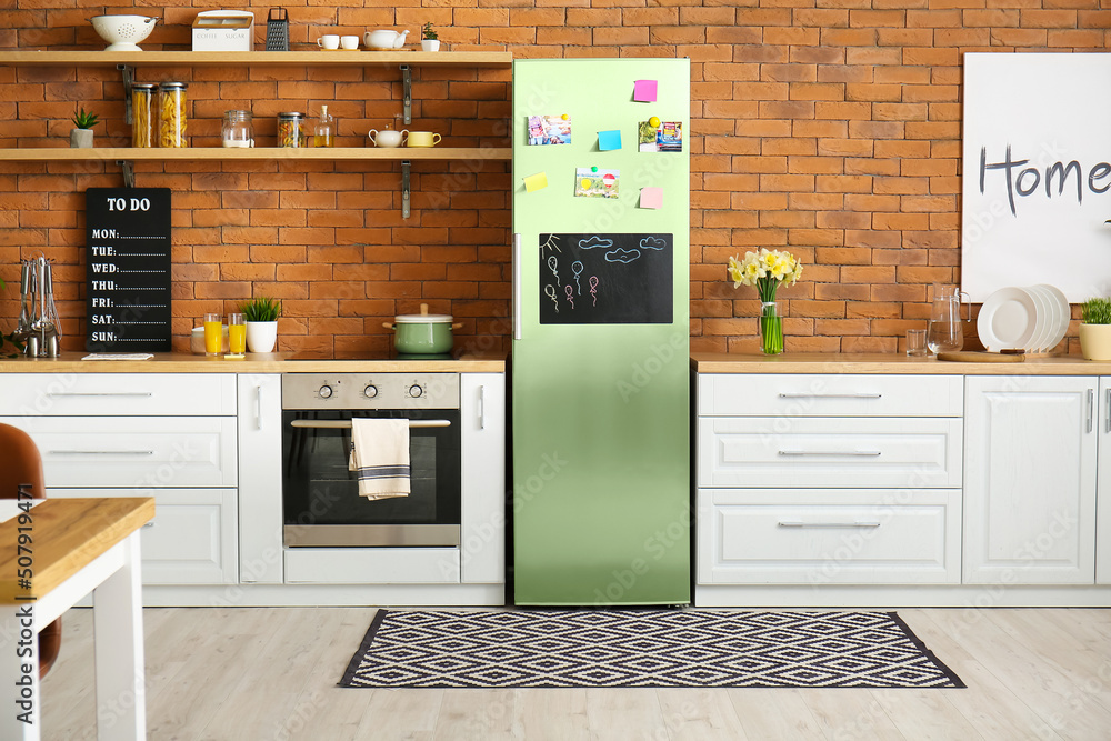 Stylish interior of modern kitchen with big refrigerator near brick wall