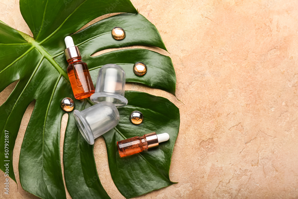 Composition with bottles of essential oil, vacuum jars for anti-cellulite massage and palm leaf on c