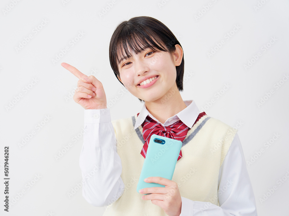 白背景でスマホを持って左側を指差す女子高生