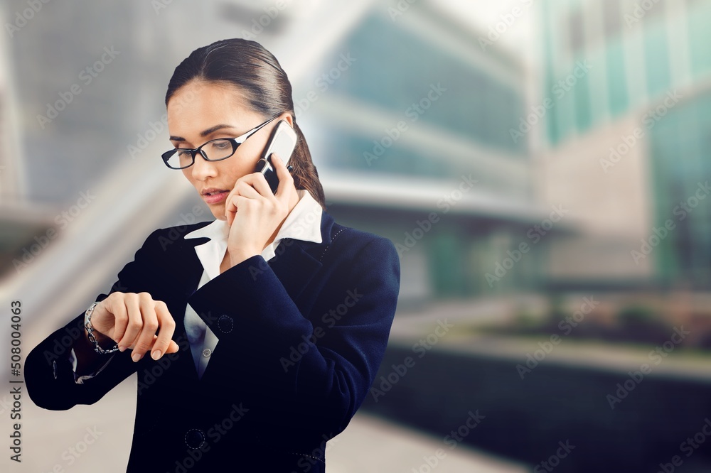 Businesswoman with phone standing on the street of a city.