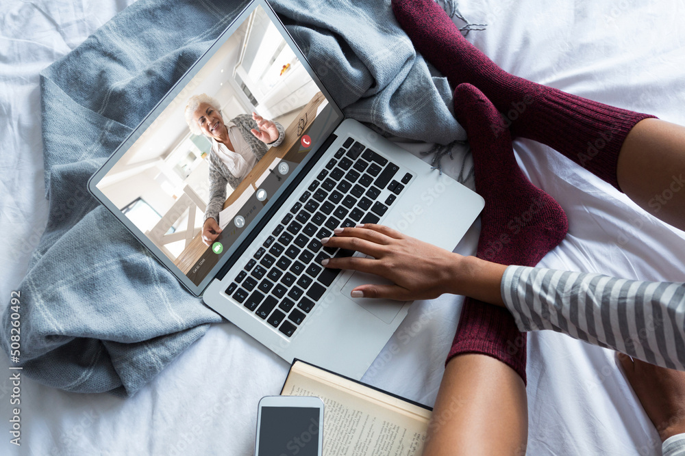 African american young woman video conferencing businesswoman while working on bed at home