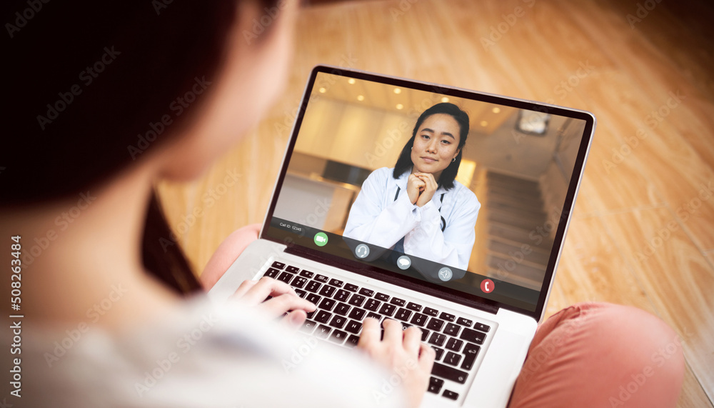 Smiling asian female doctor talking to asian woman sitting at home during video conference