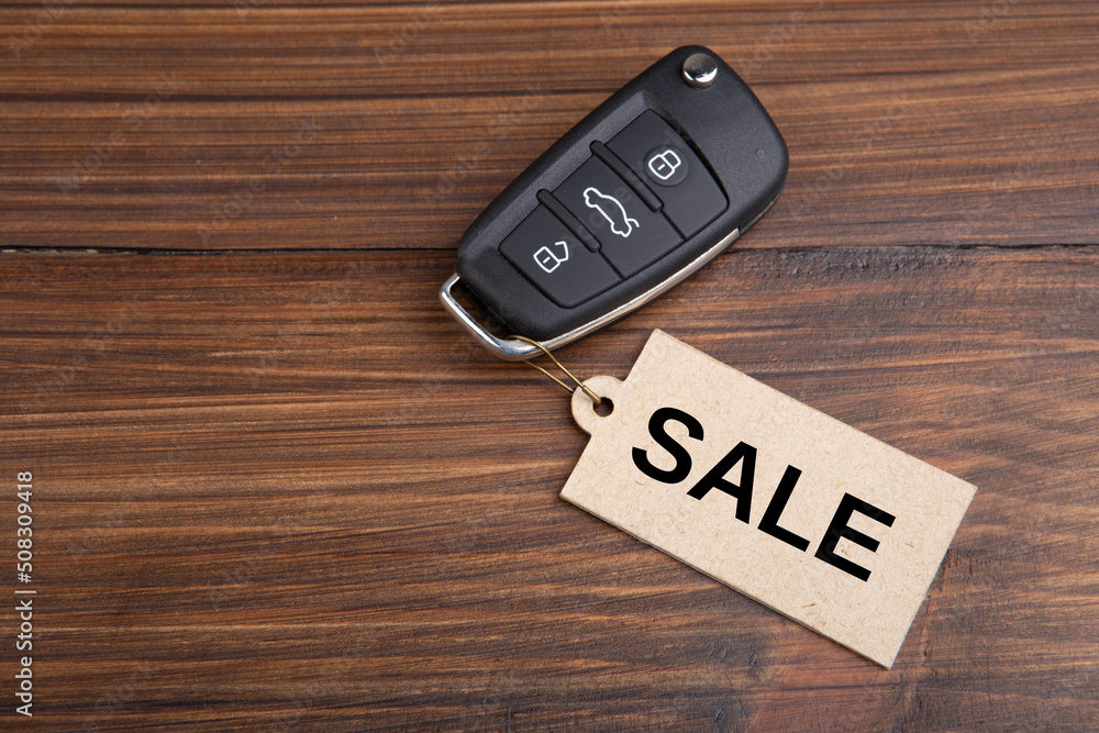 Car Sale auction concept. Vehicle security key with tag on the wooden background