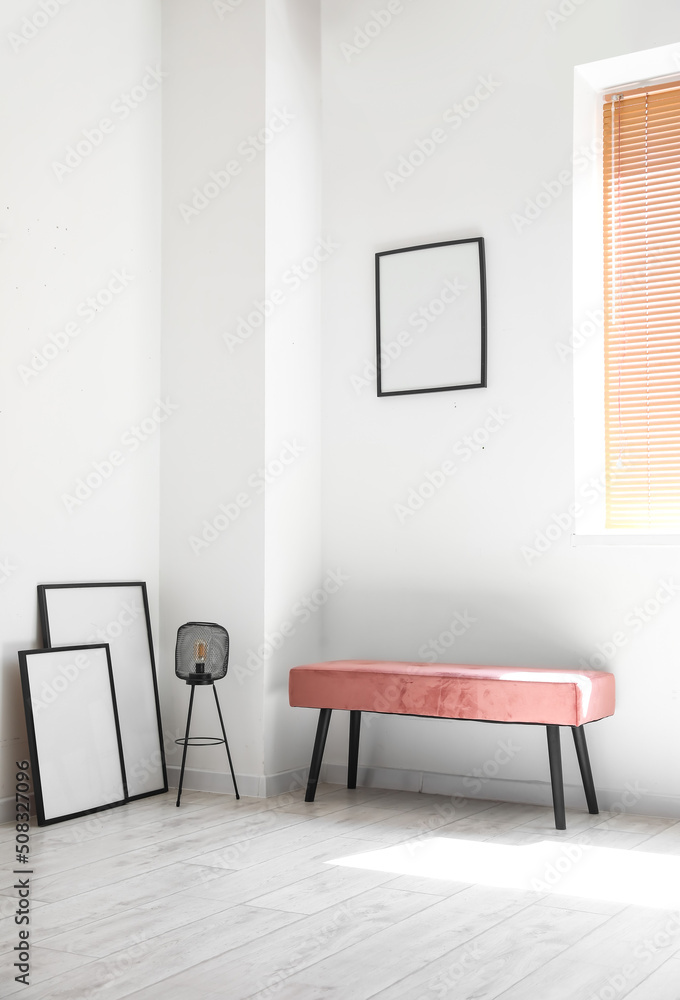 Pink bench with lamp and blank frames in light room