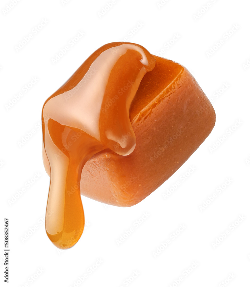 Caramel sauce flowing on caramel cube isolated on white background. Caramel candy with liquid carame