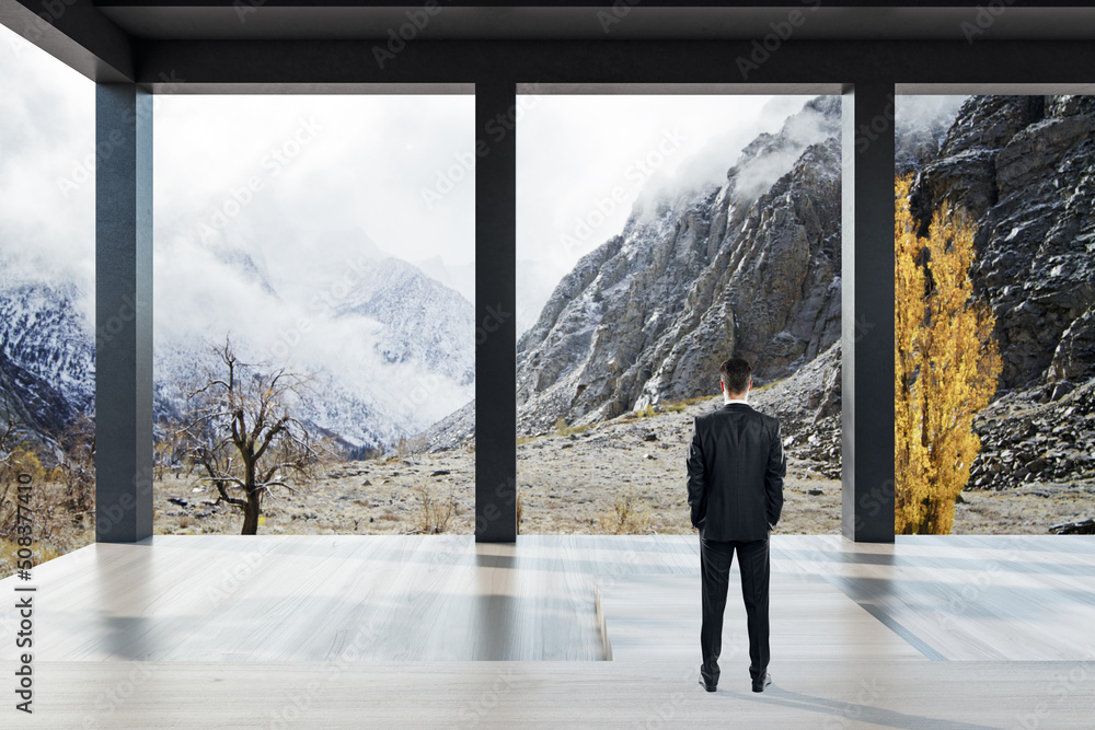 Thoughtful young european man standing in bright modern concrete terrace or balcony interior with be