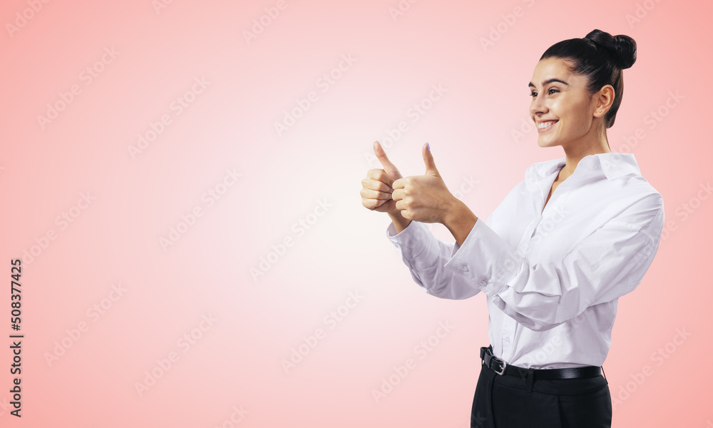 Like concept with happy girl in white shirt holding thumbs up on light pink wall background with emp