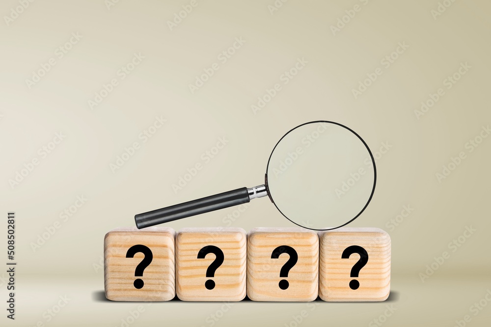 Magnifying glass on wood cubes with question marks,  test concept