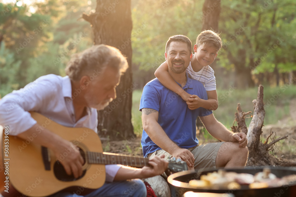 Handsome man with his little son at barbecue party on summer day