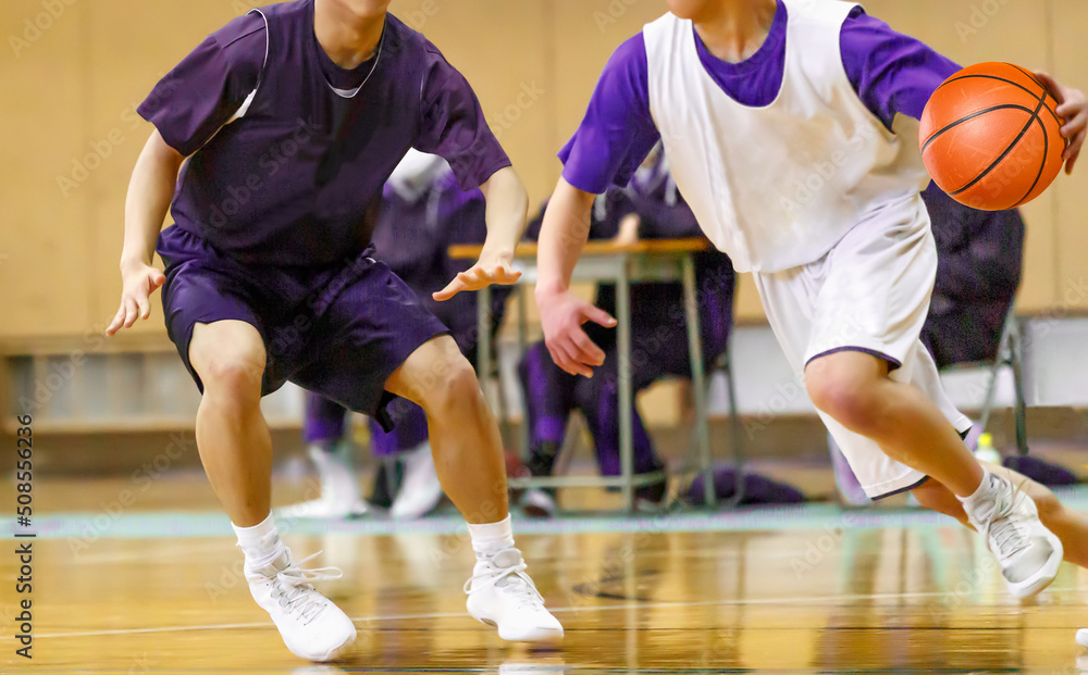 体育館でバスケットボールをする学生