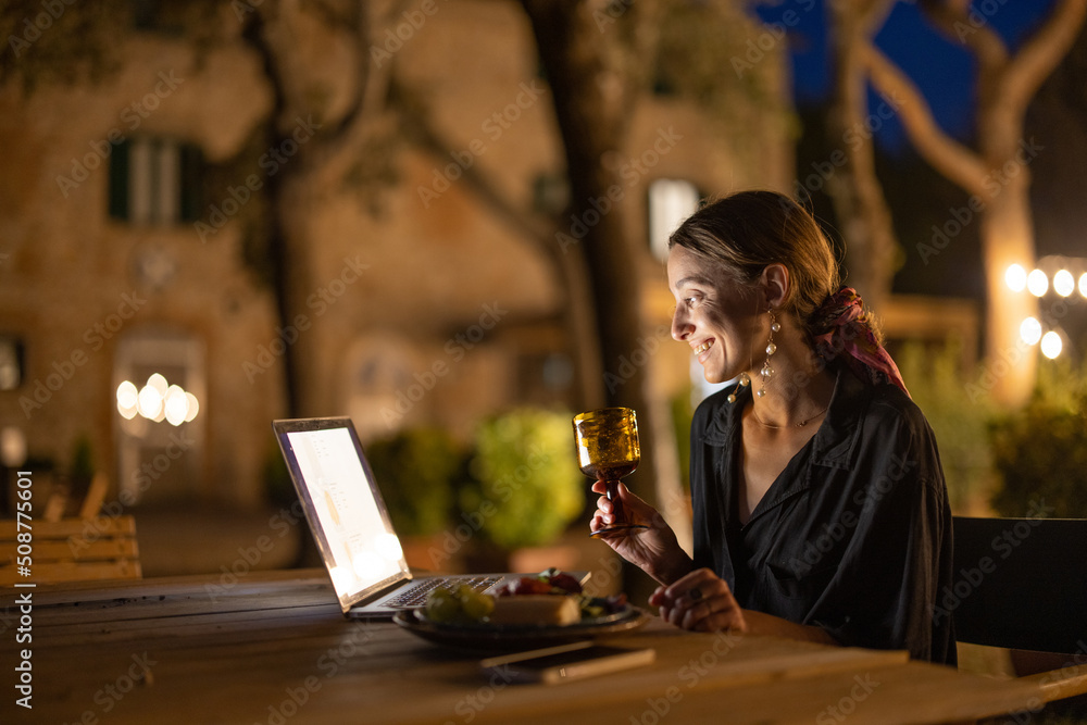 Caucasian woman watching something on laptop computer at evening time outdoors. Young woman sitting 