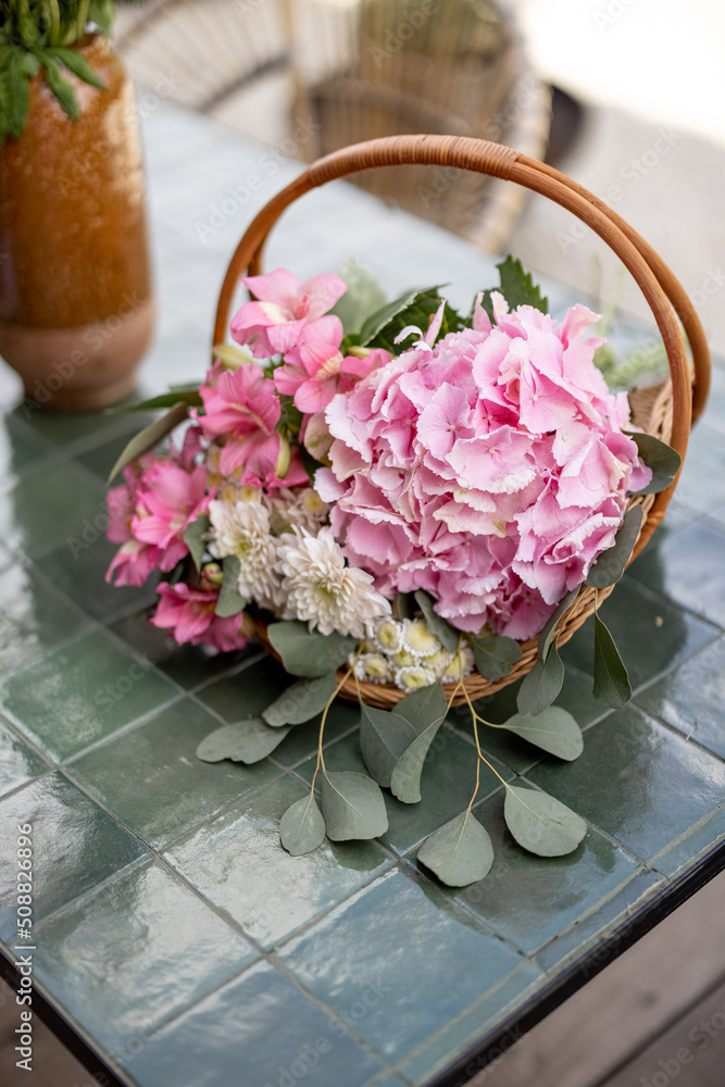 Composition of hydrangea flower with pink blossom in basket on table outdoors