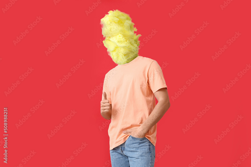 Man with tasty cotton candy instead of his head showing thumb-up on red background